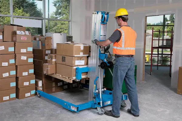 Genie SLA-15 material lift in use by warehouse worker wearing hi-vis, supplied by QuoteMeHire for safe lifting and material handling hire across the UK.
